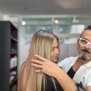 Friseur prüft die langen blonden Haare einer Kundin im Salon