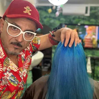 Friseur mit einer Kundin mit langen, leuchtend blauen Haaren